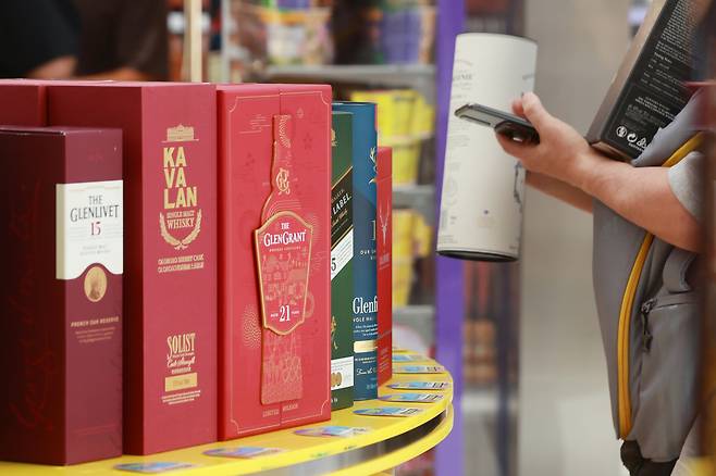 6월 서울 송파구 CU 올림픽광장점에서 열린 위스키 등 인기주류 오픈런 행사를 찾은 시민이 주류를 구매하고 있다. [연합]