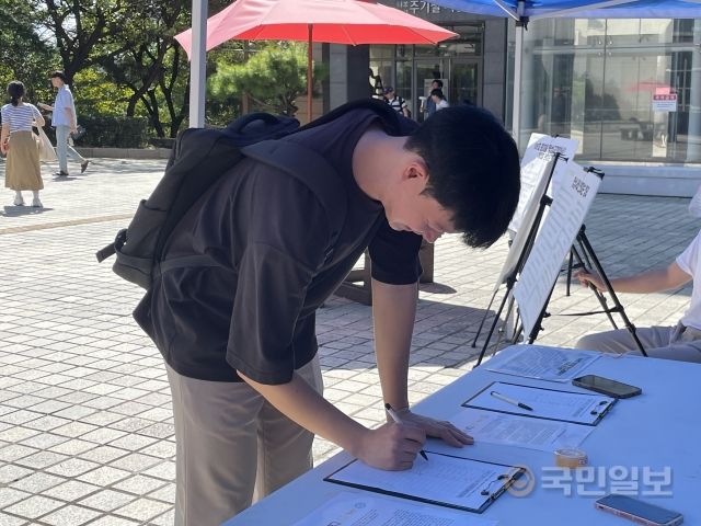 장신대 학생이 명성교회에서 열리는 총회에 대해 반대 서명하고 있다.