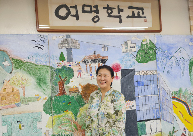 조명숙 여명학교 교장이 7일 서울 강서구의 학교 로비에서 사진을 촬영하고 있다. 조 교장 뒤로 학생들이 그린 서울 명동 교사 모습이 보인다.