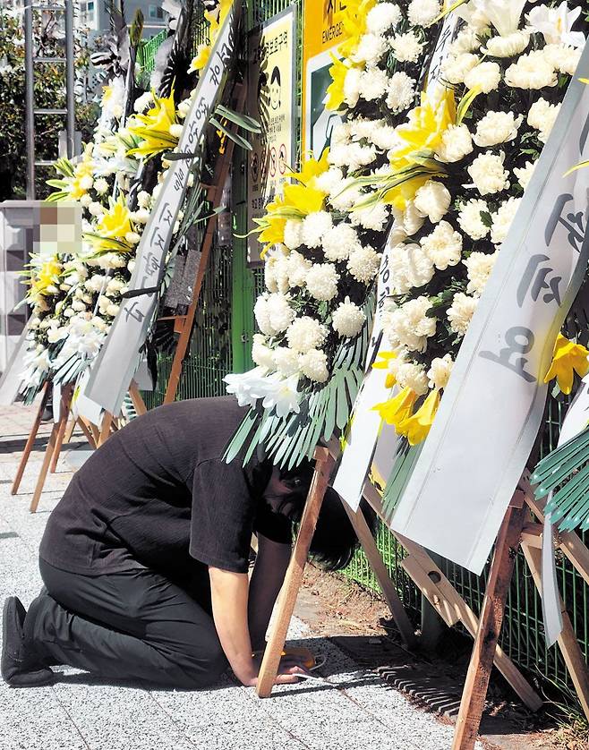 반복되는 슬픔 - 8일 오후 대전시 유성구 한 초등학교에 근무하던 40대 여교사가 극단적 선택으로 전날 사망한 가운데 동료 교사가 교문에 놓인 근조화환 앞에서 무릎을 꿇고 오열하고 있다. 해당 교사는 이전 학교에서 학부모 악성 민원과 아동학대 고소로 힘들어했던 것으로 알려졌다. /연합뉴스