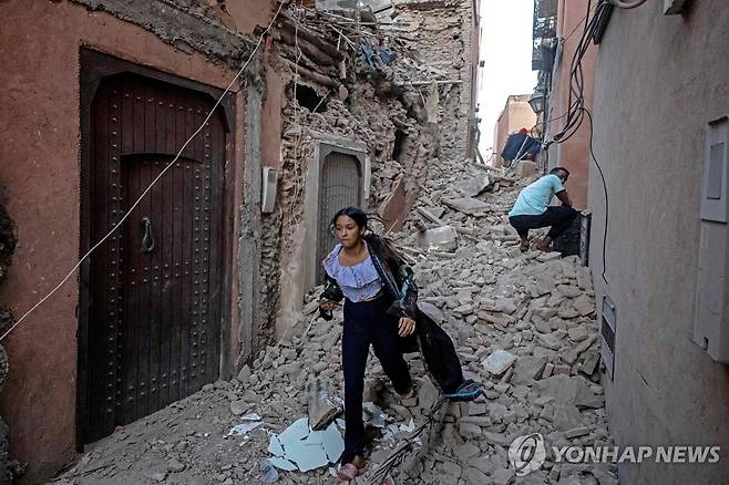 강진이 발생한 모로코 마라케시에서 무너진 건물 사이로 걸어가는 여성. [AFP 연합뉴스 자료사진. 재판매 및 DB 금지]