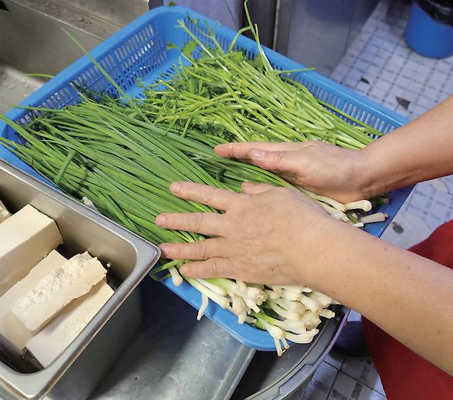업주가 최근 가격이 급등한 쪽파와 미나리 등 채소를 만지는 모습 ⓒ시사저널 오종탁