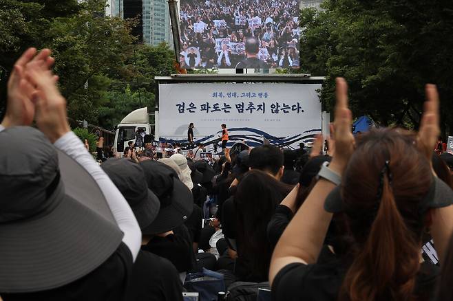 검은 옷을 입은 참석자들이 현직 초등학교 교사의 발언이 끝나자 박수 치고 있다. 김혜윤 기자