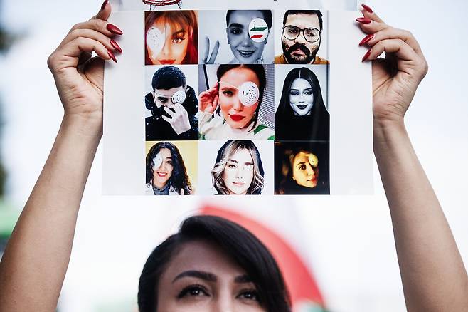 16일(현지시각) 독일 베를린에서 열린 이란 여성 마흐사 아미니의 1주기 추모 시위에서 한 여성이 아미니를 비롯한 희생자들의 사진을 들어 보이고 있다. 사진 속에는 이란 경찰이 쏜 고무총에 맞아 실명한 청년들의 사진도 있다. 아미니가 지난해 9월 히잡을 제대로 쓰지 않았다는 이유로 체포돼 의문사한 뒤 이란 전역으로 반정부 시위가 번졌다. /EPA연합뉴스