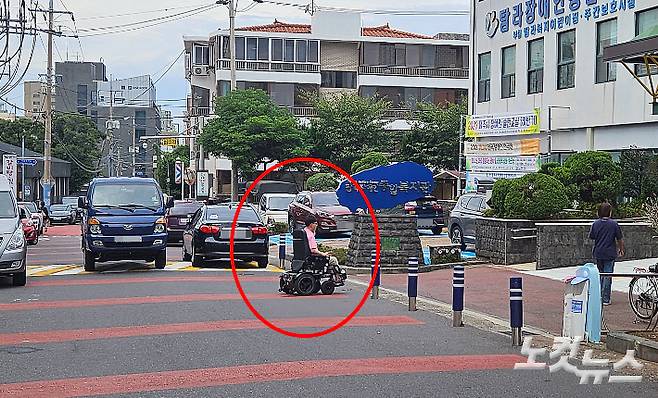 전동휠체어를 탄 장애인이 횡단보도 없는 도로를 건너고 있다. 고상현 기자