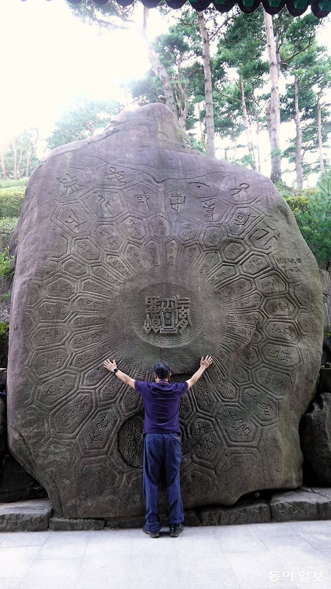 127t에 달하는 거대한 바위인 귀감석에서 좋은 기를 받기 위해 양팔을 벌리고 서 있는 관광객.
