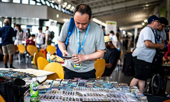 지난달 일본 요코하마에서 열린 ‘포켓몬 월드챔피언십 2023’ 참가자들이 포켓몬 카드를 살펴보고 있는 모습. 요코하마=AFP연합뉴스