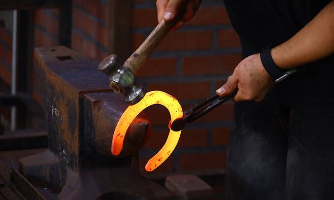 달궈진 편자를 망치로 두드려 모양을 잡아간다.