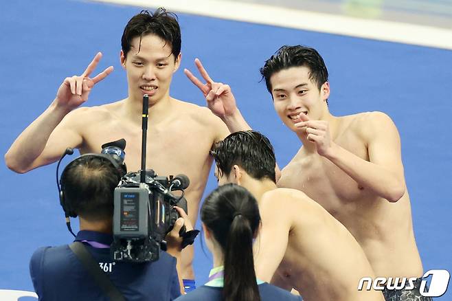 25일 오후 중국 항저우 올림픽 스포츠센터 수영장에서 열린 남자 계영 800ｍ 결승전에서 대한민국 황선우(오른쪽)와 양재훈이 금메달을 확정 지은 뒤 중계 카메라에 포즈를 취하고 있다. 2023.9.25/뉴스1 ⓒ News1 민경석 기자