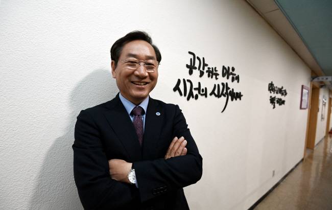 유정복 인천시장이 자신의 집무실 앞 벽면에 쓴 ‘공감하는 마음이 시정의 시작입니다’라는 글귀 앞에서 환하게 웃고 있다.  박윤슬 기자