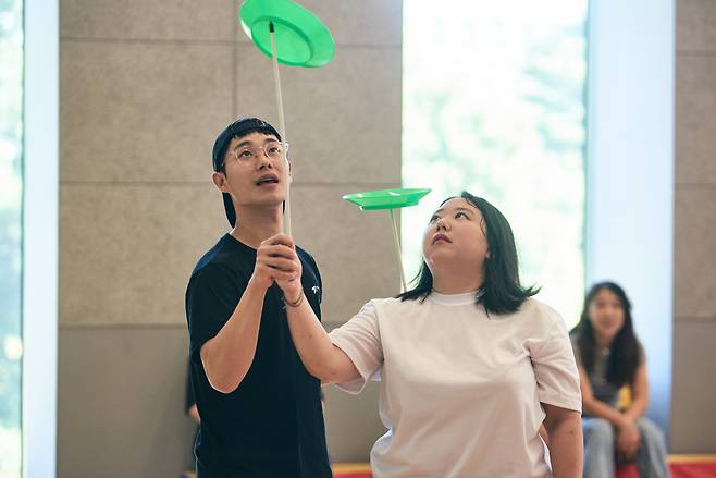 A participant tries out plate spinning while an instructor assists her during a "Circus Playground" workshop. (LG Arts Center)