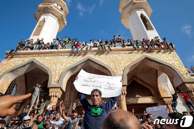 18일(현지시간) 리비아 데르나의 알 사하바 모스크 앞에서 홍수 생존자들이 "슬픈 도시 데르나는 권리를 요구한다＂라는 내용이 담긴 팻말을 들고 시위하고 있다. 2023.09.18/ ⓒ 로이터=뉴스1 ⓒ News1 장성희 기자