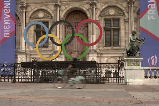 프랑스 정부가 빈대와 전쟁을 선포했다. 내년 파리 올림픽을 앞두고 파리 시청 앞에 들어선 오륜기 조형물 앞으로 지난달 13일(현지시간) 한 주민이 자전거를 타고 지나가고 있다. AP연합