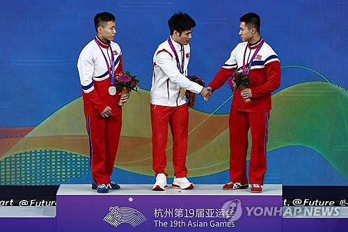 역도 메달을 획득한 중국의 리파빈(가운데)과 북한의 박명진(왼쪽), 김충국(오른쪽) [로이터=연합뉴스]