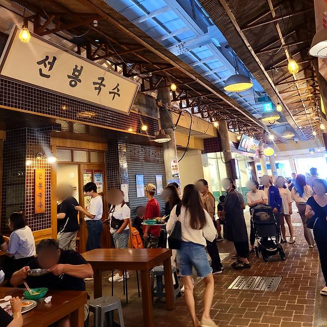 충남 예산시장 선봉국수 앞에서 지난달 25일 사람들이 점심 식사를 하기 위해 줄을 서서 기다리고 있다. /홍다영 기자