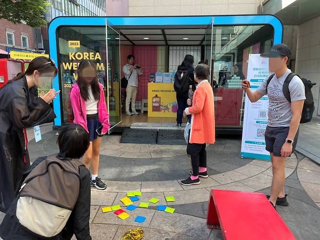 한국방문의 해 기념 환영주간, 명동 홍보 부스에서 딱지치기를 하는 외국인 관광객.