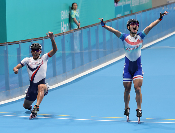 Korea's Jung Cheol-won, right, crosses the finish line in the men's speed skating 3,000-meter relay at Qintang Roller Sports Centre in Hangzhou, China, finishing 0.1 seconds behind Chinese Taipei to take silver in the event.  [YONHAP]