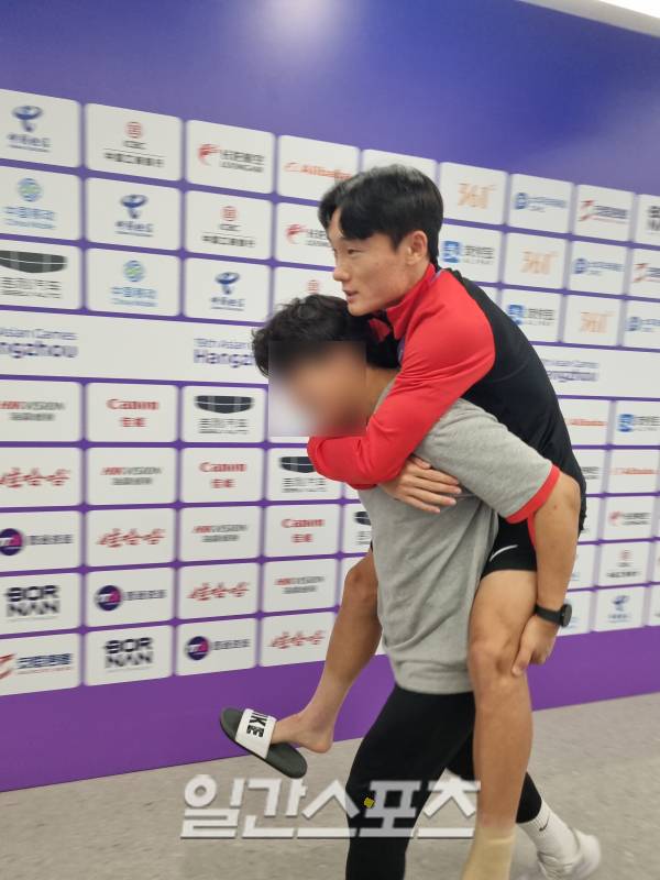 4일 우즈베키스탄전에서 강한 태클을 받은 엄원상(위)이 경기 후 업혀서 믹스트존을 빠져나가고 있다. 항저우(중국)=차승윤 기자