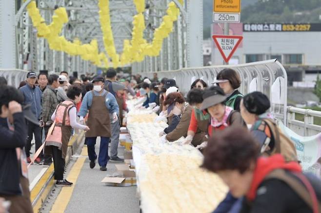 7일 충남 공주시 금강철교 위에서 열린 '인절미 축제'에서 시민과 관광객들이 인절미를 만들고 있다. 이날 만든 인절미는  '단일 장소에서 동시에 만들어진 가장 긴 인절미' 부문 한국기록원 공식 최고 기록을 수립했다.[사진출처=공주시 제공, 연합뉴스]