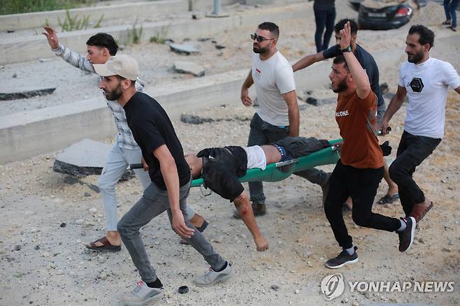 이스라엘군의 공습으로 부상한 팔레스타인 주민을 옮기는 사람들  (AFP=연합뉴스)