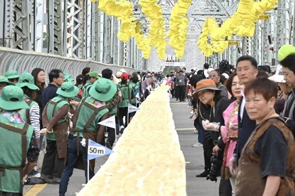 지난 7일 충남 공주시 금강철교 위에서 열린 인절미 축제에서 시민들이 국내에서 가장 긴 인절미 만들기 행사에 참여하고 있다. [사진=공주시]