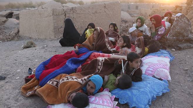 지진 피해를 입은 아프가니스탄 헤라트주 여성들과 아이들이 8일(현지시간) 땅바닥 위에서 쉬고 있다. 신화연합뉴스