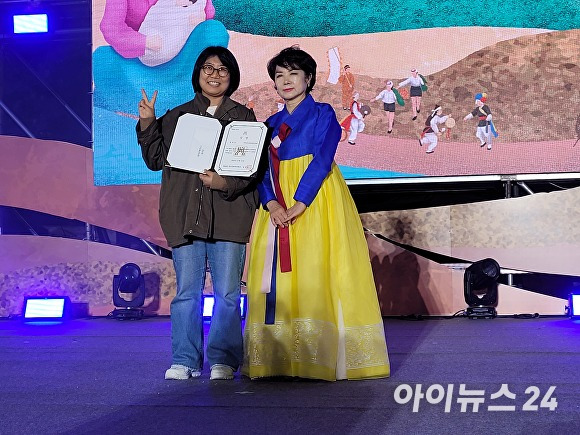 김선영 탐라문화제 대회장(오른쪽)이 '성산읍민속보존회&제주성산한마음민속회' 관계자에게 탐라퍼레이드 대상을 시상하고 포즈를 취하고 있다.   [사진=박태진 기자]