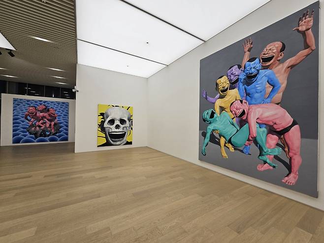 An installation view of "Yue Minjun Solo Exhibition" at Tang Contemporary Art in Seoul with an oil painting "Enjoy Myself" on the right (Park Yuna/The Korea Herald)