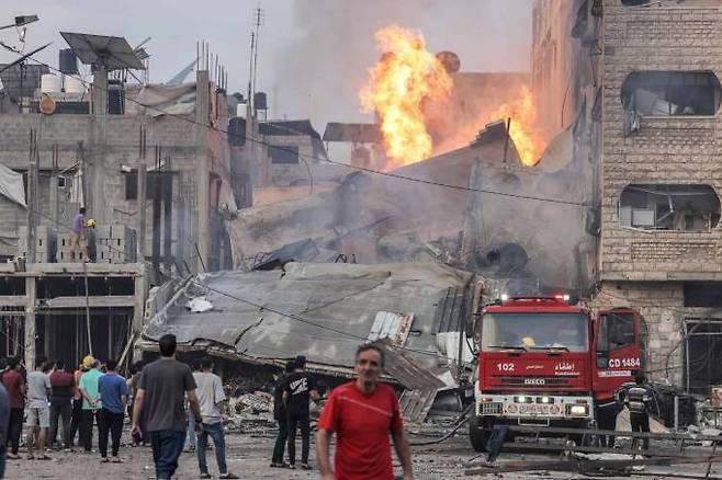 11일 이스라엘이 가자시티를 폭격한 이후 사람들이 불타는 붕괴된 건물 밖에 소방차가 배치되는 것을 지켜보고 있다. 밤사이 이스라엘의 공격으로 인해 최소 30명이 사망하고 수백 명이 부상을 입었다. 연합뉴스