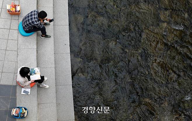 서울 중구 청계천 일대에 마련된 야외도서관 ‘책읽는 맑은냇가’를 찾은 시민들이 13일 책을 읽거나 스마트폰을 보며 시간을 보내고 있다.