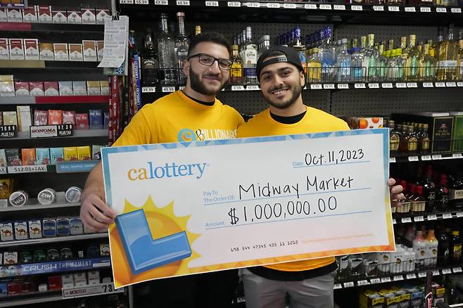 11일(현지시간) 파워볼 1등 당첨자가 나온 캘리포니아 프레이저 파크의 미드웨이 마켓&리쿼의 공동 소유자 가족인 조나단 칼릴(왼쪽)과 크리스 칼릴이 기념 사진을 촬영하고 있다. [AP]