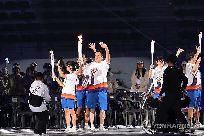 전국체전 성화 밝히는 선동열 (목포=연합뉴스) 정회성 기자 = 선동열(가운데) 전 야구 국가대표 감독이 13일 오후 전남 목포시 목포종합경기장에서 열린 제104회 전국체육대회 개회식에서 성화 봉송 주자로 나서고 있다. 2023.10.13 hs@yna.co.kr