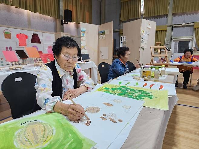 ‘할망그림 예술창고’에 전시할 제주 밭작물 그림을 그리고 있는 홍태옥(86·왼쪽)·김인자(84·가운데)·강희선(86)씨. 김인자씨는 “우리 셋은 3년 전에 밭작물 그림을 가장 먼저 그리기 시작한 삼총사”라며 웃었다.