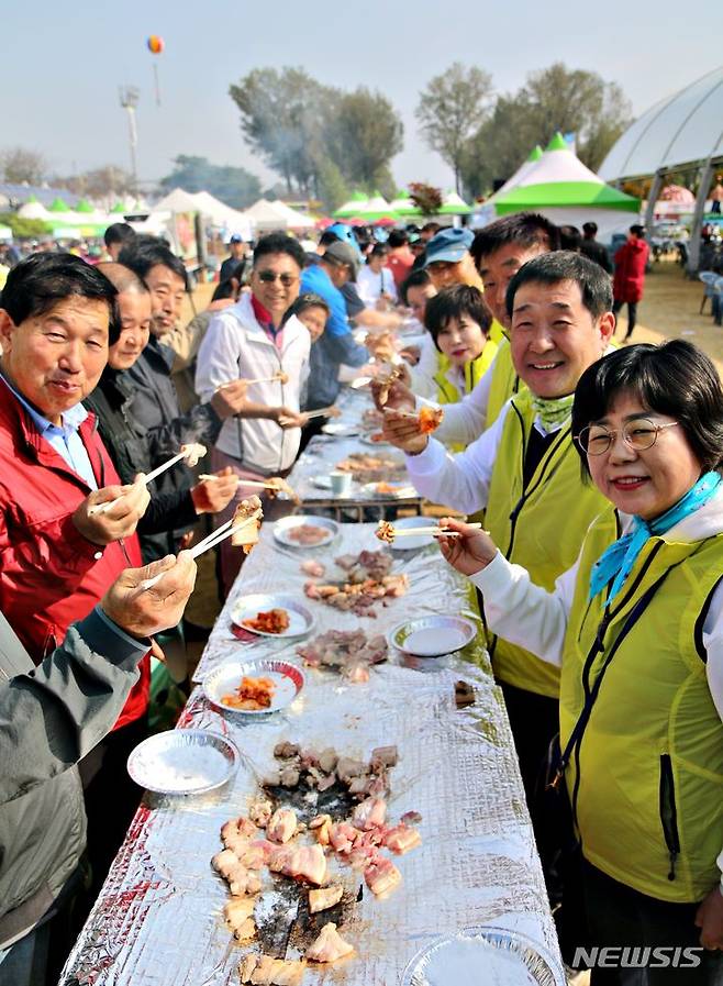 [증평=뉴시스] 강신욱 기자 = 14일 충북 증평군 증평읍 보강천체육공원에서는 2023 증평인삼골축제 하이라이트인 17회 홍삼포크삼겹살대잔치가 성황리에 열리고 있다. 이재영 증평군수, 이동령 증평군의회의장, 김장응 증평문화원장 등 지역 기관·단체장들이 주민, 관광객들과 대형 구이틀에 둘러 서서 지역 특산품인 홍삼포크삼겹살을 시식하고 있다. 이번 행사는 5년 만에 다시 선보였다. 2023.10.14. ksw64@newsis.com