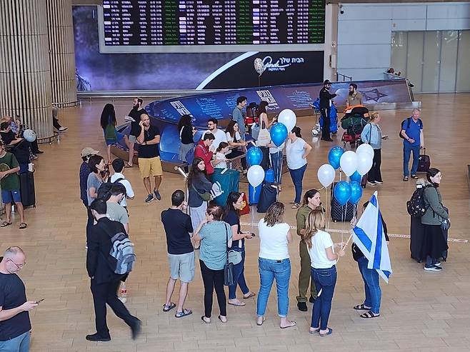 참전을 위해 귀국하는 이스라엘 남성들을 맞이하기 위해 국기와 풍선 등을 들고 벤구리온 공항 입국장에 나온 사람들. [촬영 김상훈]