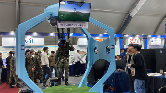 A Korean soldier demonstrates Ares’s parachute simulator at its booth set at the Seoul ADEX 2023 at Seoul Air Base in Seongnam, Gyeonggi, on Tuesday. [CHO JUNG-WOO]