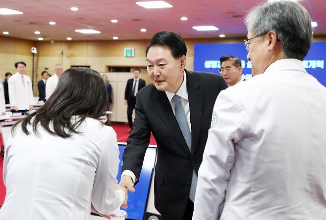 윤석열 대통령이 19일 충북 청주 충북대학교 개신문화관에서 열린 생명과 지역을 살리는 필수의료혁신 전략회의에 입장하며 참석자들과 인사하고 있다. [연합]