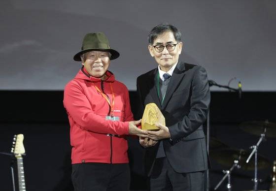전날(20일) 울산 울주군 영남알프스 복합웰컴센터에서 열린 '제8회 울산울주세계산악영화제' 개막식에서 특별 공로상으로 선정된 산악인 김영도 고문(99세)을 대신해 아들이 무대에 올라 대리 수상을 하고 엄홍길 집행위원장과 기념촬영을 하고 있다. 뉴스1