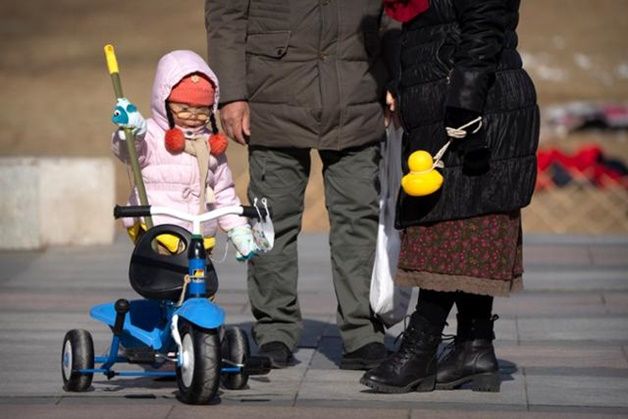 중국 베이징의 한 공원에서 한 아이가 할머니 할아버지의 보살핌을 받으며 세발자전거를 타고 있다. ⓒ AP/뉴시스