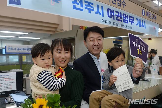 [전주=뉴시스] 김얼 기자 = 우범기 전주시장이 23일 전북 전주시 전주시청 민원실에서 '전주시 여권업무 개시' 기념 퍼포먼스를 열고 1호 여권 발급자와 기념촬영을 하고 있다. 2023.10.23. pmkeul@newsis.com