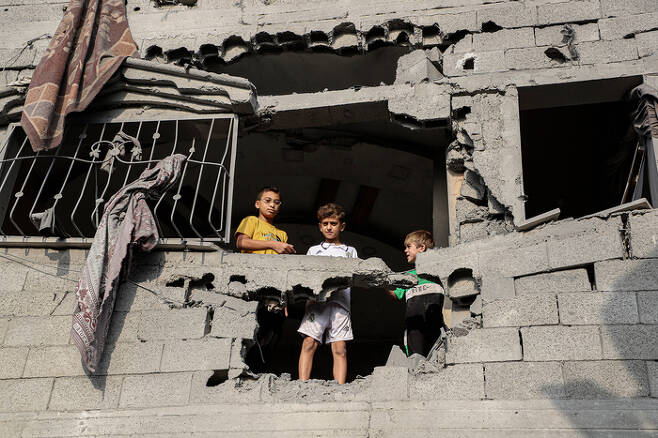 25일(현지시간) 가자지구 남부 도시 칸 유니스에서 이스라엘군의 공습을 받아 부서진 한 건물 위에 소년들이 서 있다. 신화연합뉴스