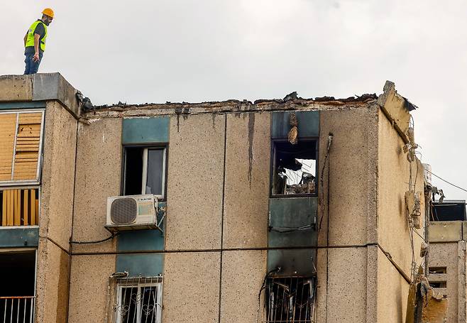 한 이스라엘 구조대원이 27일(현지시각) 하마스의 로켓에 맞아 파손된 텔아비브의 아파트 옥상에 서 있다. 이 공격으로 4명이 부상을 입었다. /EPA 연합뉴스