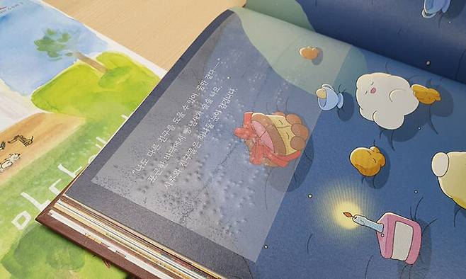 지난 24일 인천시 미추홀구 송암점자도서관에서 사회복지사가 ‘시루와 커다란 케이크’라는 제목의 그림책 페이지에 점자 라벨을 붙이고 있다.