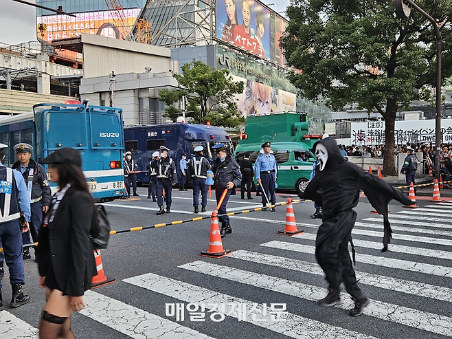 일본 시부야 스크램블 교차로에서 경찰이 설치한 펜스 앞을 핼러윈 분장을 한 사람이 지나가고 있다. [도쿄 이승훈 특파원]