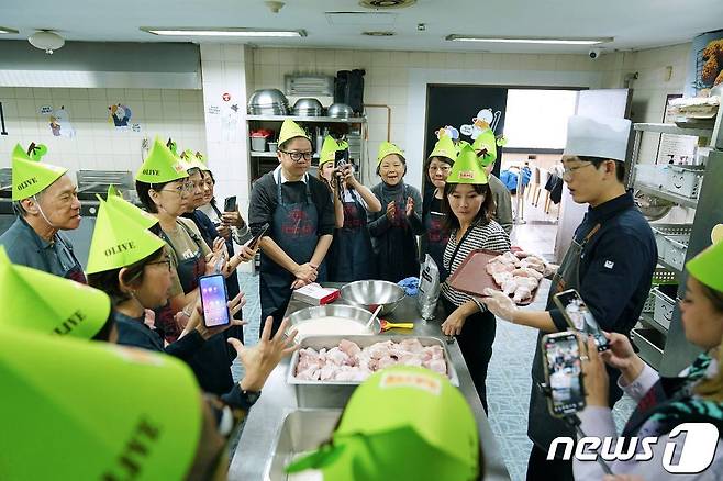 BBQ치킨_한국을 방문한 싱가폴 관광객들이 BBQ 치킨대학의 치킨캠프에 참여해 BBQ 황금올리브 치킨 조리 방법을 배우고있다.(BBQ제공)