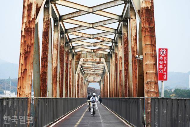 자전거 여행자들이 북한강철교 위를 달리고 있다. 녹슨 트러스가 오래된 구조물의 푸근함을 풍긴다.