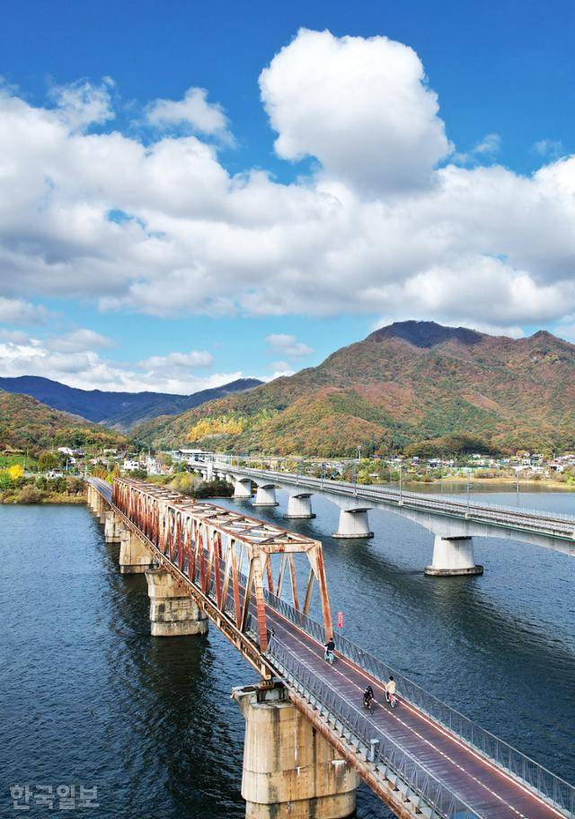 자전거 여행자들이 북한강철교 위를 달리고 있다. 강 건너 남양주 운길산이 울긋불긋 단풍으로 물들고 있다.