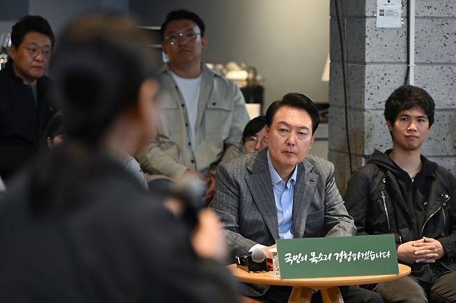 윤석열 대통령이 1일 서울 마포구의 한 카페에서 제21차 비상경제민생회의를 열고 참석자들의 발언을 메모하며 듣고 있다. 이날 회의에는 소상공인, 택시기사, 무주택자 등 다양한 직업과 연령대의 시민들이 참여했다./대통령실