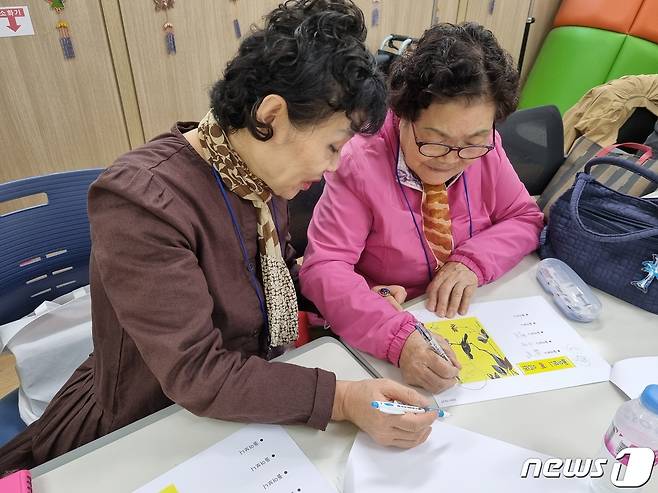 대구 수성구 범어노인복지관 프로그램인 '돌아보니 봄이더라' 참여자가 자원봉사자의 도움을 받아 자서전을 만들고 있다.(대구 수성구 제공)