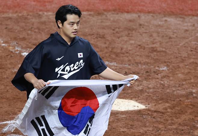 한국 야구 대표팀 문동주가 10월7일 중국 저장성 항저우 인근 사오싱 야구·소프트볼 스포츠센터 제1구장에서 열린 2022 항저우아시안게임 대만과 결승전에서 2-0으로 승리하며 금메달을 차지한 뒤 그라운드에서 태극기를 들고 있다. 항저우/연합뉴스